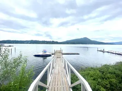 a dock with a boat on a lake at Executive 1 Bedroom Lakeview Retreat in Shawnigan Lake