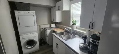 a small kitchen with a sink and a washing machine at The Bainbridge Studio in Burnaby