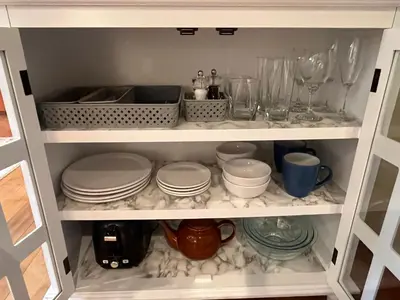a white cabinet filled with plates and dishes at A Seaside Jacuzzi Escape in Parksville, BC, Canada in Parksville