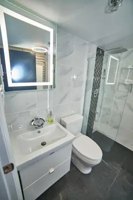 a white bathroom with a toilet and a sink at Upscale Modern Apartment in Whistler