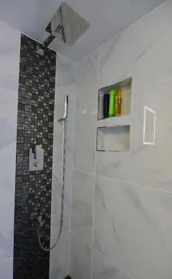a white bathroom with a shower with a glass door at Upscale Modern Apartment in Whistler