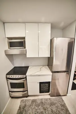 a kitchen with white cabinets and a stainless steel refrigerator at Upscale Modern Apartment in Whistler
