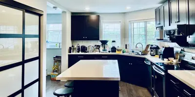 a kitchen with black cabinets and a white counter top at Vancouver airport 7mins away joy room in Richmond