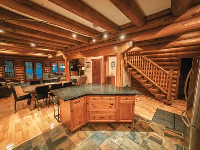 a log cabin kitchen with a staircase in the background at GrizzPaw Lodge - Mountain Resort - 5 Bedroom Chalet - Sleeps 14 People in Golden