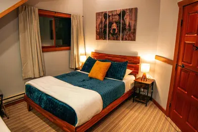 a bedroom with a bed with blue and yellow pillows at GrizzPaw Lodge - Mountain Resort - 5 Bedroom Chalet - Sleeps 14 People in Golden