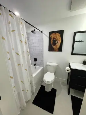 a bathroom with a toilet and a lion painting on the wall at Spacious Forested Garden Suite in North Vancouver