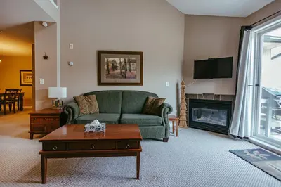 a living room with a green couch and a fireplace at Peaks of Radium by StayIn in Radium Hot Springs
