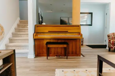 a wooden piano in a living room with stairs at Central Calgary & Nearby Mountain Escape - 4 Beds in Calgary