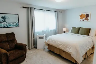 a bedroom with a bed and a chair and a window at Central Calgary & Nearby Mountain Escape - 4 Beds in Calgary