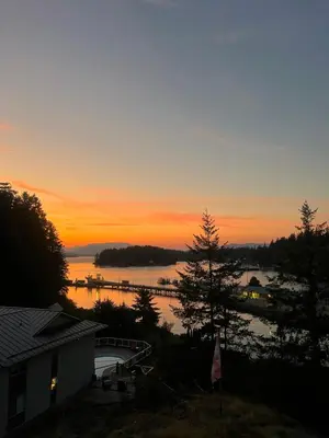 a sunset over a body of water with a house at High Pont Resort in Quathiaski Cove
