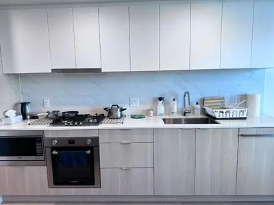 a kitchen with white cabinets and a stove and a sink at New condo near Lougheed Mall & SFU in Coquitlam