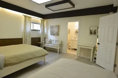 a bedroom with two beds and a chair and a window at Bright Spacious 3 BR Garden Suite, 4 Queen beds, Fully equipped, Highly recommended by 229 happy groups in Burnaby