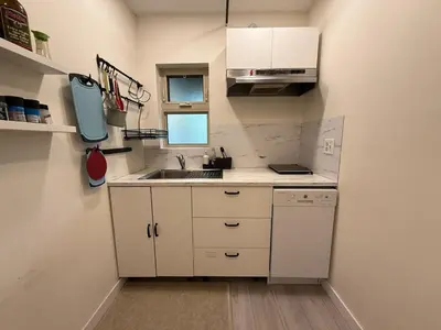 a small kitchen with white cabinets and a sink at Bright Spacious 3 BR Garden Suite, 4 Queen beds, Fully equipped, Highly recommended by 229 happy groups in Burnaby