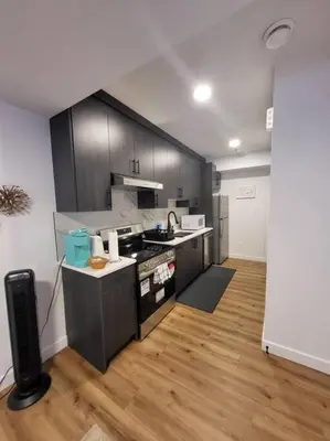 a kitchen with black cabinets and a wooden floor at Pebbles' Cozy 2Bed Basement Suite - near Downtown in Edmonton