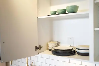 a white kitchen with plates and bowls on a shelf at Water Views From Every Window in Victoria