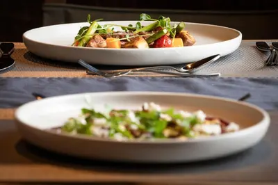 two plates of food on a table with a salad at The Lodge at Bow Lake in Lake Louise