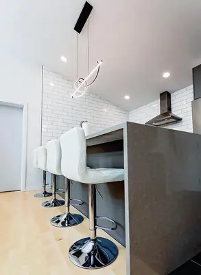 a kitchen with a counter with white bar stools at LuxQuarters Bumbleberry Guest House in Kitimat