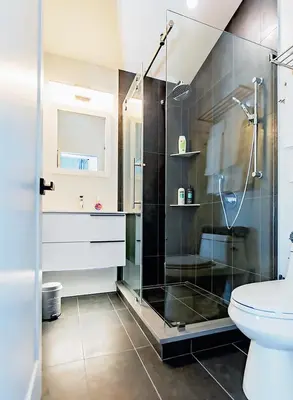 a bathroom with a glass shower and a toilet at LuxQuarters Bumbleberry Guest House in Kitimat