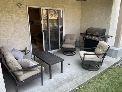 a patio with a grill and chairs and a table at Chris Cozy Condo Commonwealth #107 Edmonton in Edmonton
