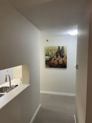 a white kitchen with a painting on the wall at Chris Cozy Condo Commonwealth #107 Edmonton in Edmonton
