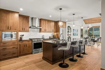 a kitchen with wooden cabinets and a large island with bar stools at Spring Creek Luxury - managed by Little Sister Getaways in Canmore