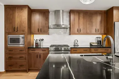 a kitchen with wooden cabinets and a stove at Spring Creek Luxury - managed by Little Sister Getaways in Canmore
