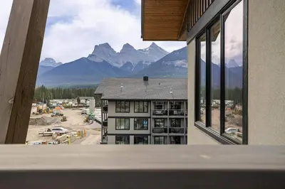 a view of a building with mountains in the background at Spring Creek Luxury - managed by Little Sister Getaways in Canmore