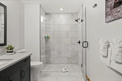 a white bathroom with a shower and a toilet at Spring Creek Luxury - managed by Little Sister Getaways in Canmore
