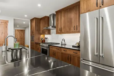 a kitchen with wooden cabinets and a stainless steel refrigerator at Spring Creek Luxury - managed by Little Sister Getaways in Canmore