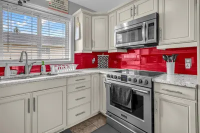 a kitchen with white cabinets and red walls at 33 Executive Home, Ac, Airport in Calgary