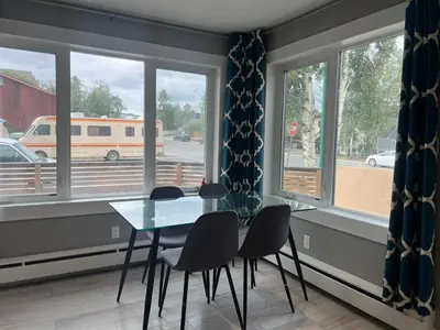 a dining room with a table and chairs and windows at Little Holiday Home in Yellowknife
