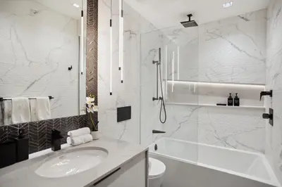 a white bathroom with a sink and a shower at Designer 2BR in Downtown Steps from Sunset Beach in Vancouver