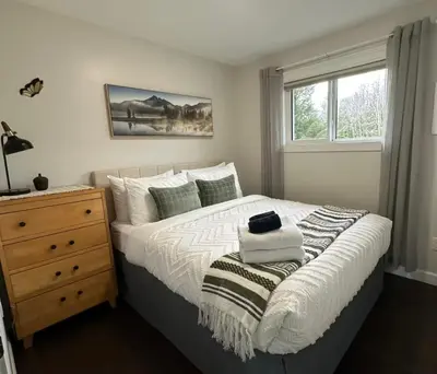 a bedroom with a bed with a dresser and a window at Caribou Lodge in Terrace