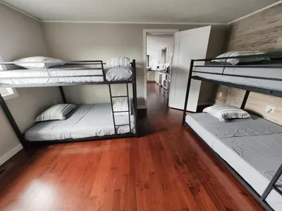 a room with three bunk beds and a wooden floor at EC Lodging in Yellowknife