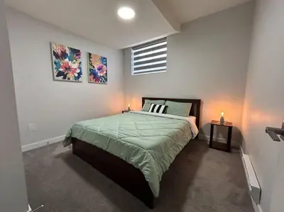 a bedroom with a bed and two pictures on the wall at Comfortable and centrally located guest suite in Calgary