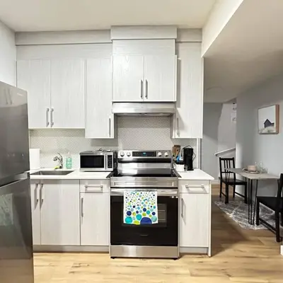 a kitchen with white cabinets and a stove top oven at Comfortable and centrally located guest suite in Calgary
