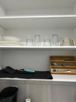 a kitchen shelf with plates and bowls and utensils at A Luxurious Cozy Place in Calgary