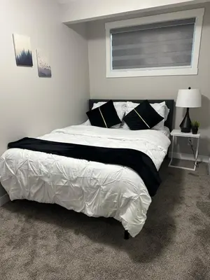 a bedroom with a large white bed with black pillows at A Luxurious Cozy Place in Calgary