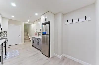a kitchen with white walls and a stainless steel refrigerator at Executive Bliss Suites in Calgary