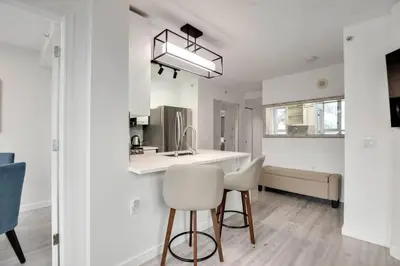 a kitchen with white counters and white chairs in a room at Luxury Condo in Downtown Vancouver with city view in Vancouver