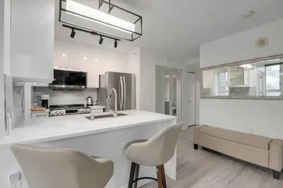 a white kitchen with white appliances and white chairs at Luxury Condo in Downtown Vancouver with city view in Vancouver