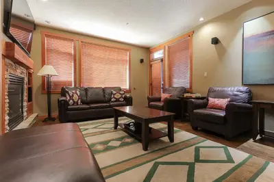 a living room with leather furniture and a flat screen tv at Slalom Creek 2 Bedroom & Den in Rossland