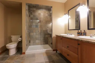 a bathroom with a shower and a toilet and two sinks at Slalom Creek 2 Bedroom & Den in Rossland