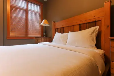 a bedroom with a large white bed with a wooden headboard at Slalom Creek 3 Bedrooms in Rossland