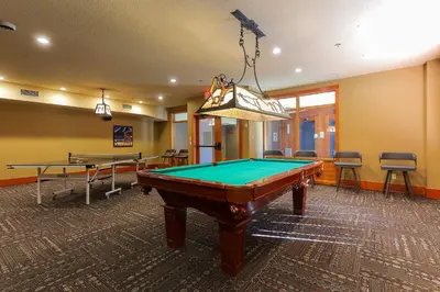 a pool table in a room with two tables at Slalom Creek 3 Bedrooms in Rossland