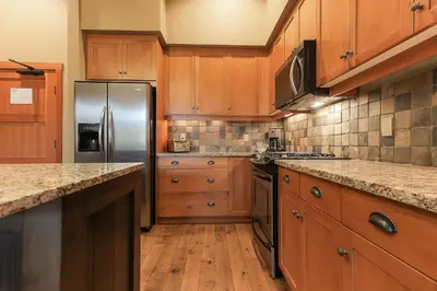 a kitchen with wooden cabinets and a stainless steel refrigerator at Slalom Creek 2 Bedrooms in Rossland
