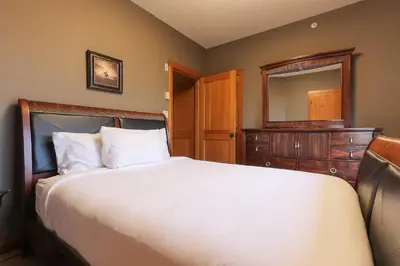 a bedroom with a bed and a dresser and a mirror at Slalom Creek 2 Bedrooms in Rossland