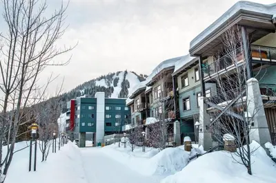 a snow covered street with buildings and a mountain at Slalom Creek 3 Bedroom in Rossland