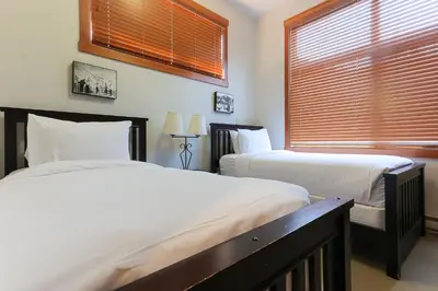 a bedroom with two beds and a window with blinds at Slalom Creek 3 Bedroom in Rossland