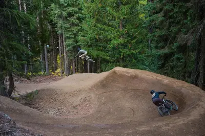 two people on bikes and a skateboard in the air at White Wolf in Rossland